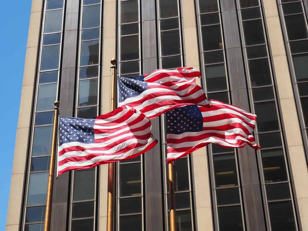 Three US flags blowing in the wind.