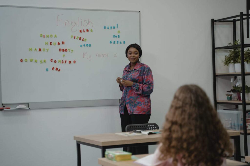English teacher standing in front of whiteboard.