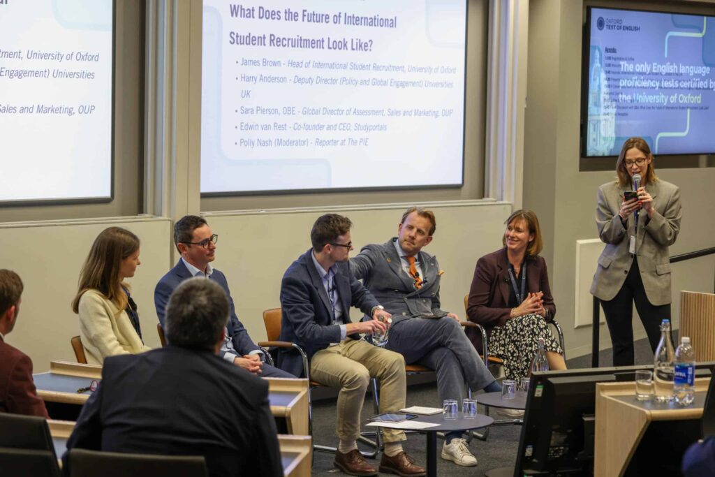 Five panelists speaking at a conference.