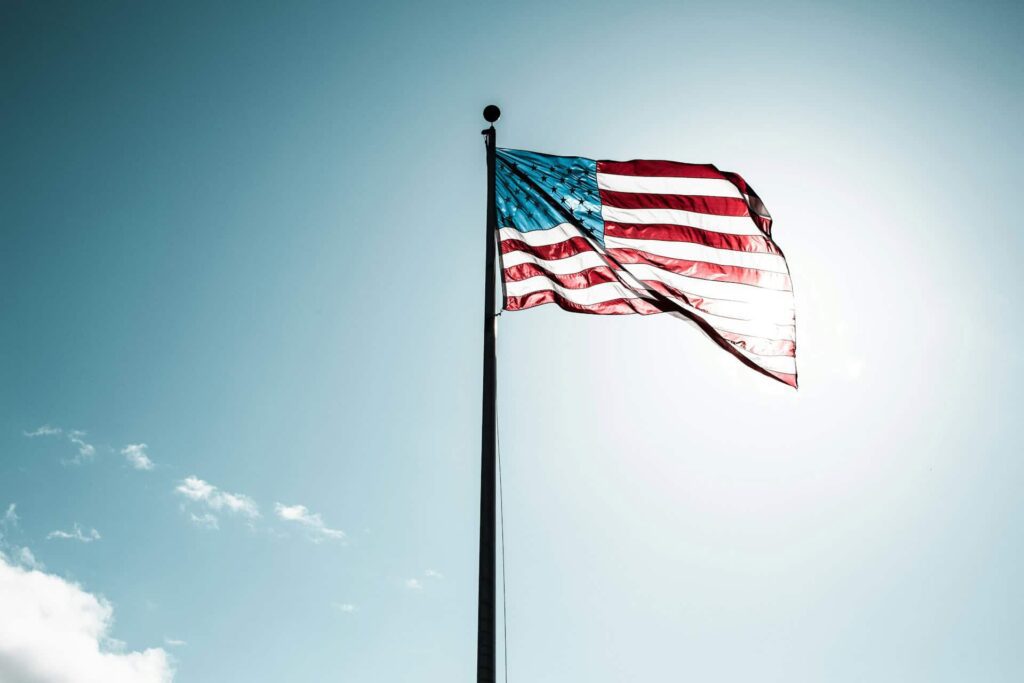 US flag against sunny blue sky.