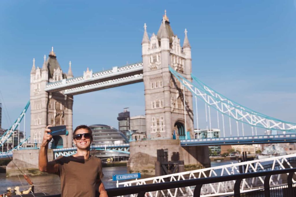 Man taking selfie in front of Tower Bridge, London, UK.