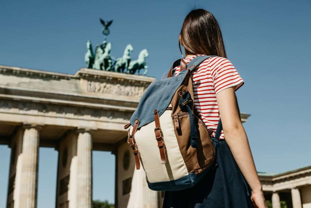 Woman with backpack looking at Brandenburg Gate, Berlin.