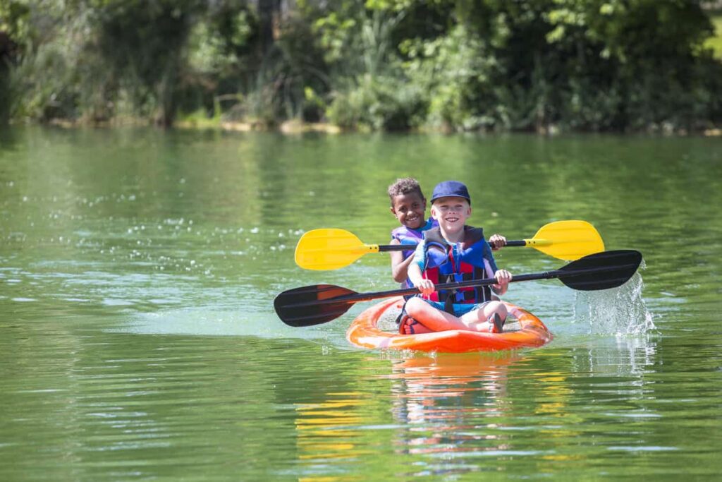 Children in double kayak on river.