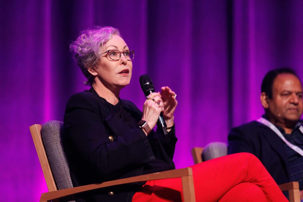 Claire Field speaks on stage with microphone