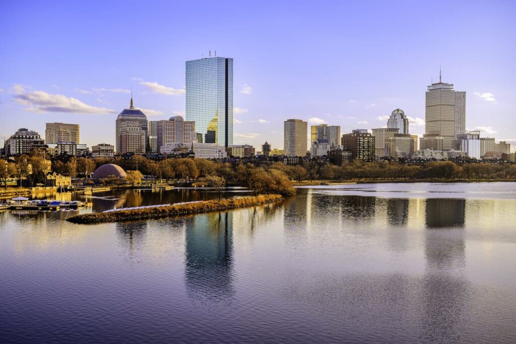 Boston City Skyline over the Charles River in Massachusetts, USA. A tranquil riverscape of Back Bay with golden illuminated wintery foliage in New England.